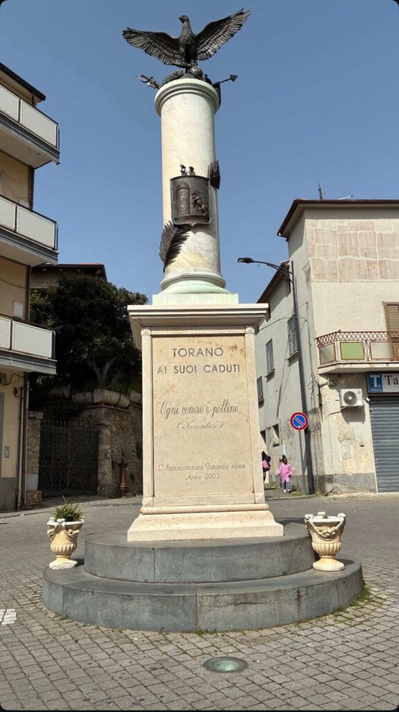 Monumento ai caduti di Torano CS con colonna sormontata da aquila e iscrizione frontale